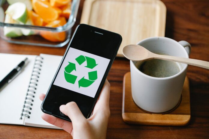 crop person using recycling app on smartphone against coffee