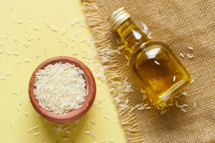 clear mini glass bottle with oil on sackcloth beside a bowl of rice grains